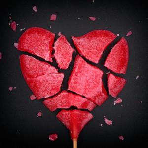 Broken red heart shaped lollipop. Closeup. Vignette.
